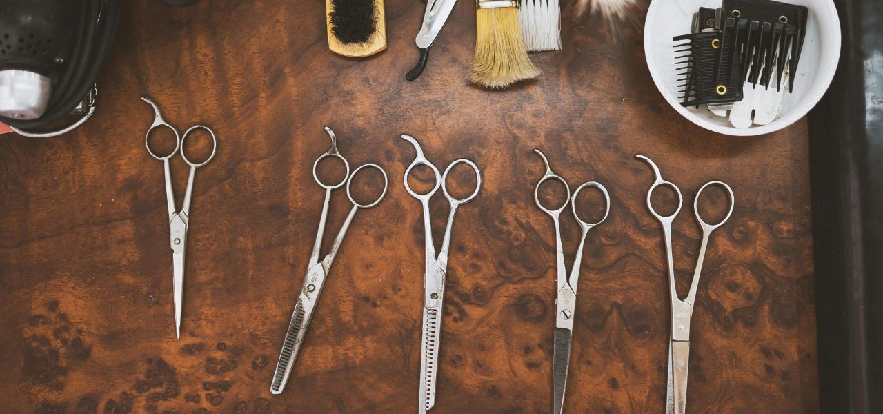 A collection of vintage barber tools including scissors and brushes on a wooden surface.